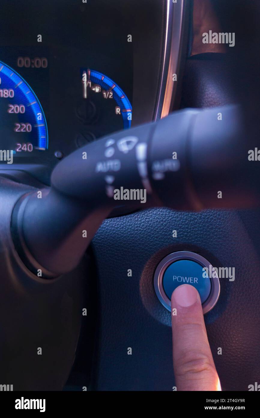 Drücken Sie mit dem Finger auf die Auto-Start-Taste. Umweltfreundliches Fahrkonzept Stockfoto