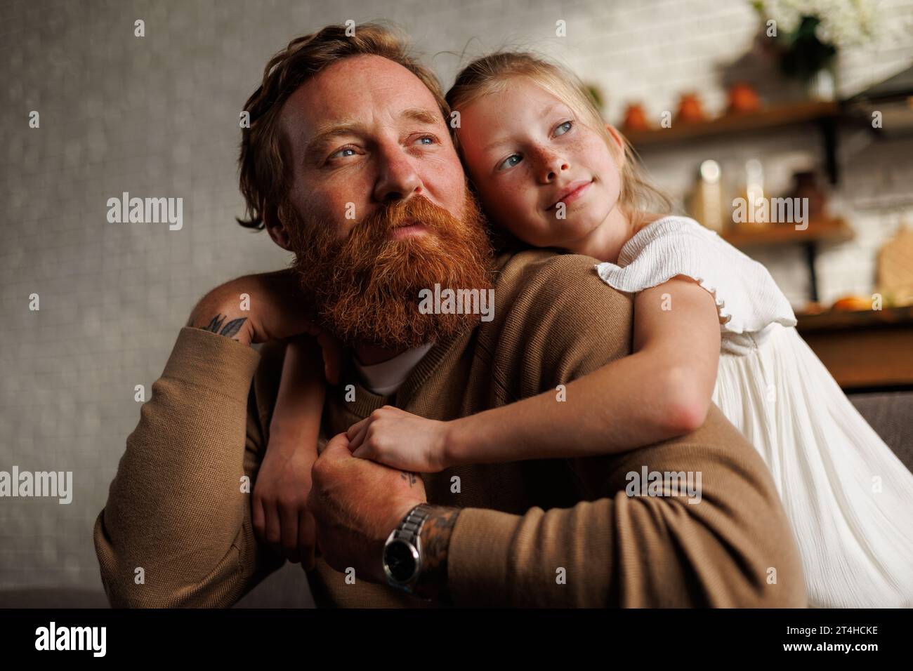 Porträt eines Kindes, das zu Hause einen bärtigen und tätowierten Vater umarmt Stockfoto