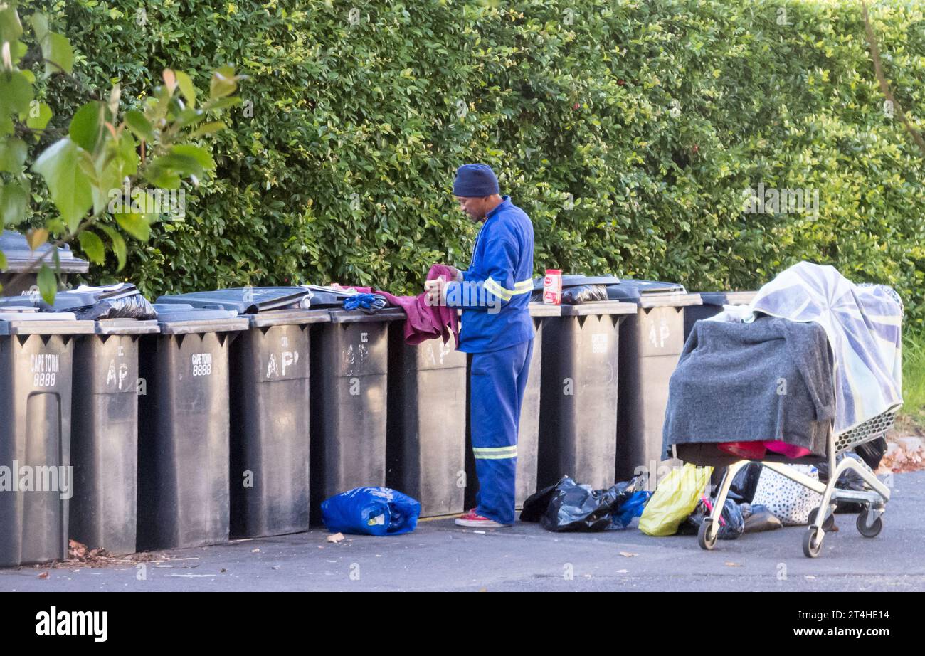 Authentische Street-Life-Szene eines afrikanischen Mannes, der in Kapstadt in Mülltonnen nach Essen sucht, Südafrika Konzept Lifestyle oder Alltag in Afrika Stockfoto