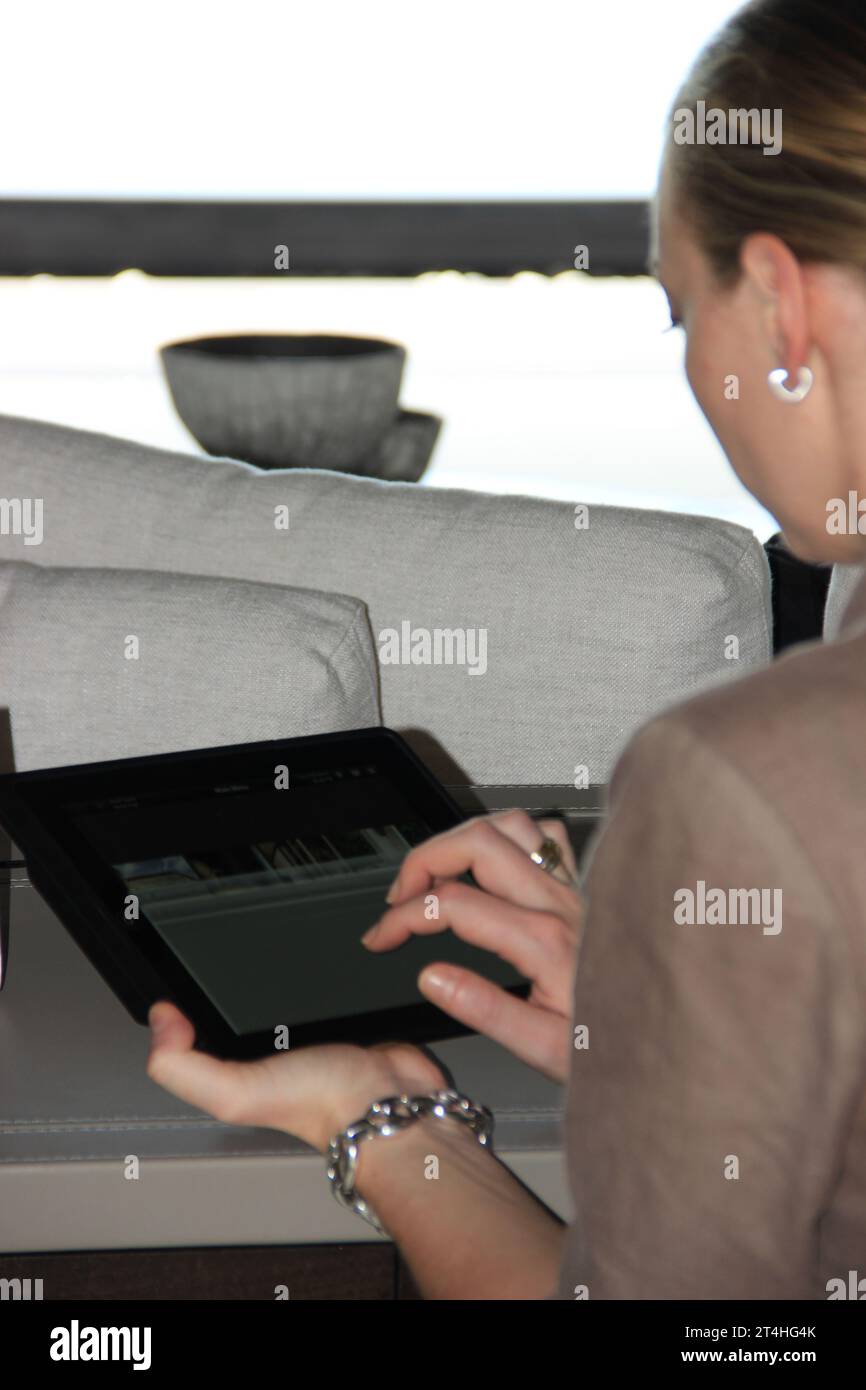 Seychellen, La Digue - 05. Oktober 2022: Frau, die zu Hause ein Tablet benutzt und auf den Bildschirm tippt Stockfoto