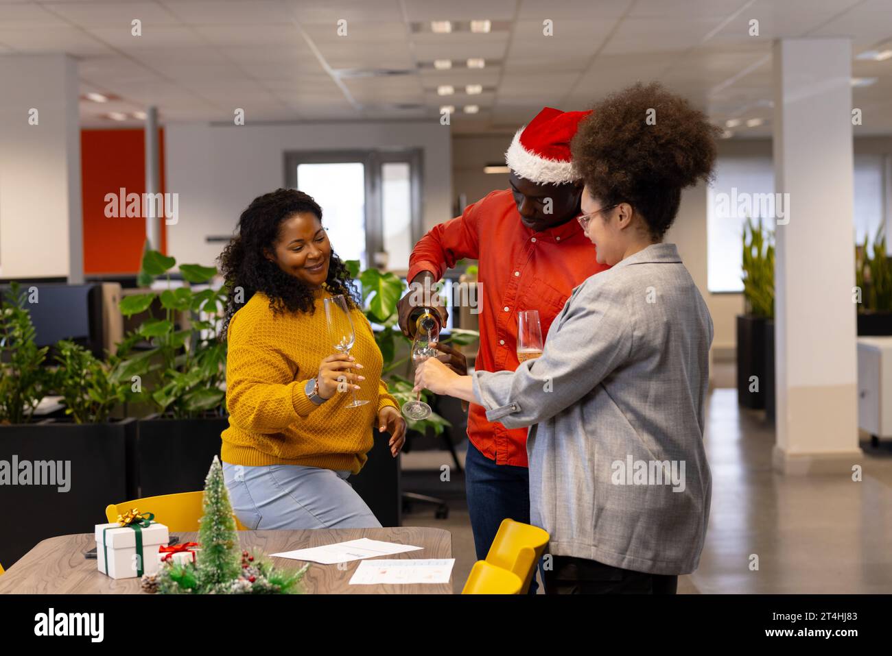 Drei glückliche, vielseitige Geschäftsleute mit Gläsern und Champagner im Büro, Kopierraum Stockfoto