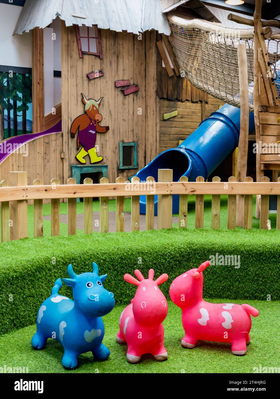 Das Innere eines Teils der Einrichtungen, die in der Spielscheune des Monty's Farm Park angeboten werden, mit rosafarbenem und blauem Spielzeug für Kleinkinder im Vordergrund Stockfoto