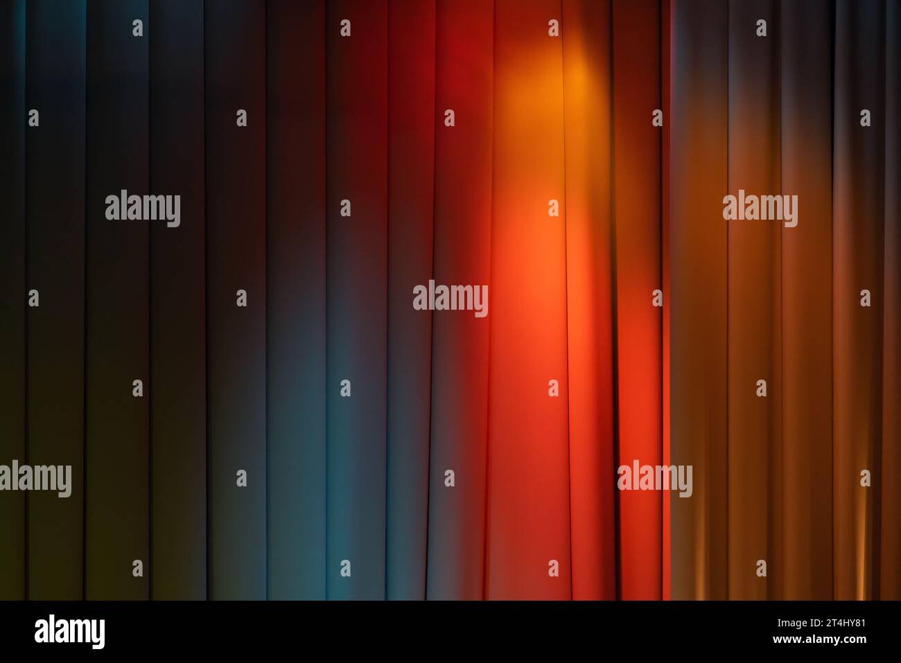 Geschlossener welliger Theatervorhang mit Bühnenbeleuchtung aus bunten Spots, Hintergrundfotostruktur Stockfoto