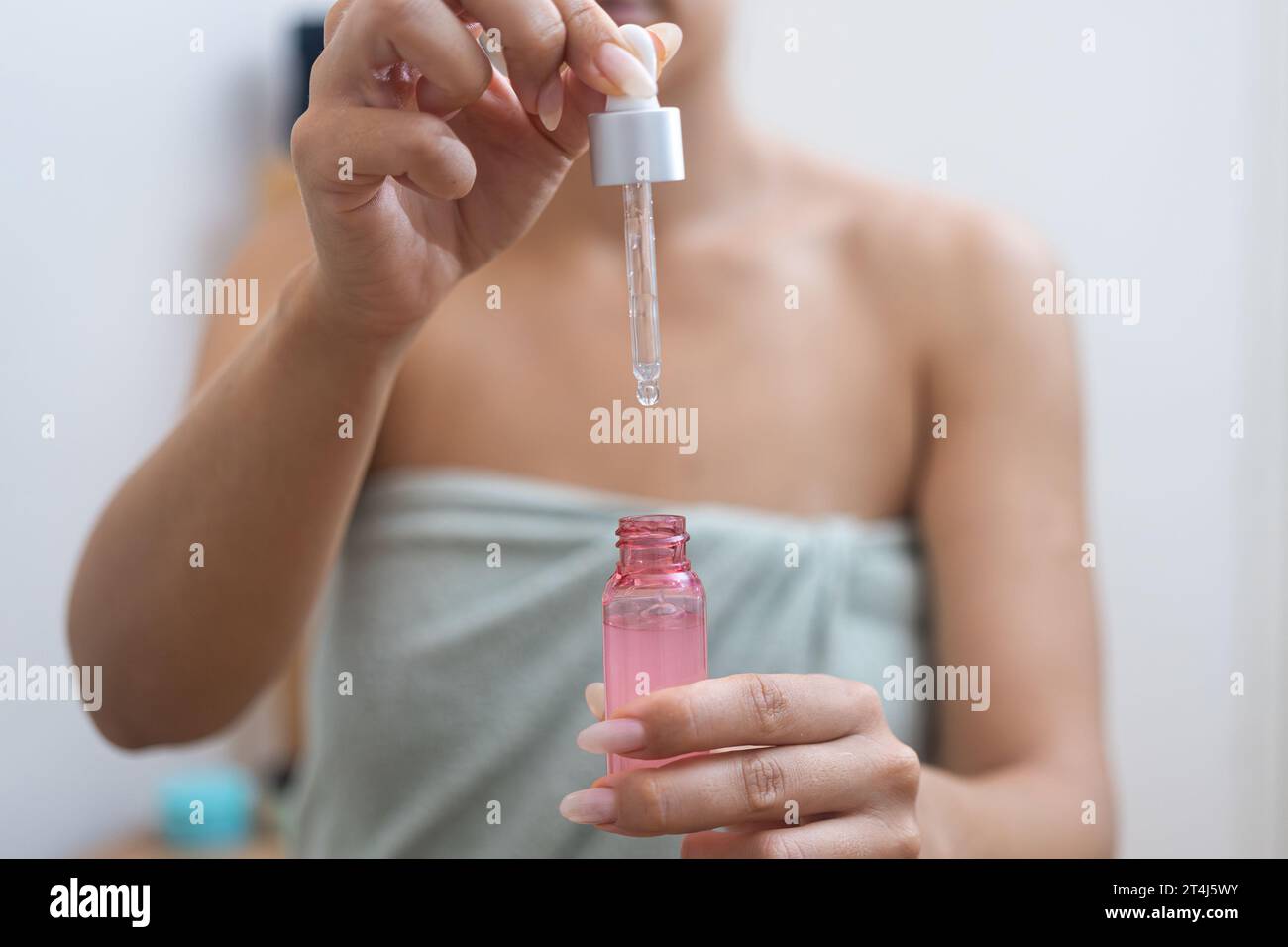 Frau perfektioniert ihre Anti-Aging-Hautpflege, indem sie Hyaluronsäure mit einem Serumtropfer aufträgt. Stockfoto