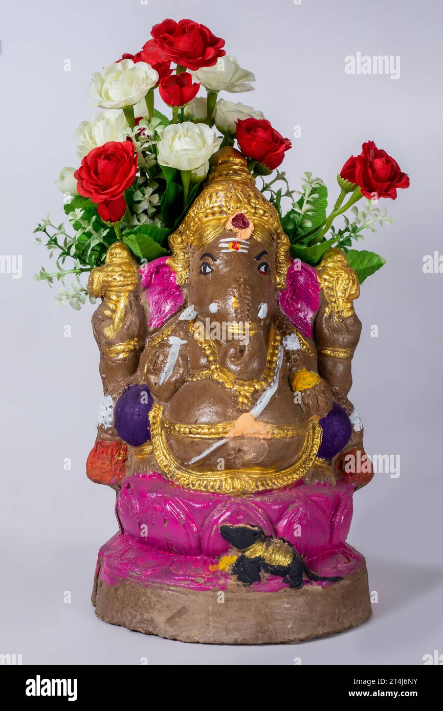 Happy Ganesh Chaturthi - indischer Hindugott Lord Ganesh Statue aus Lehm mit Blumen auf weißem Hintergrund. Stockfoto