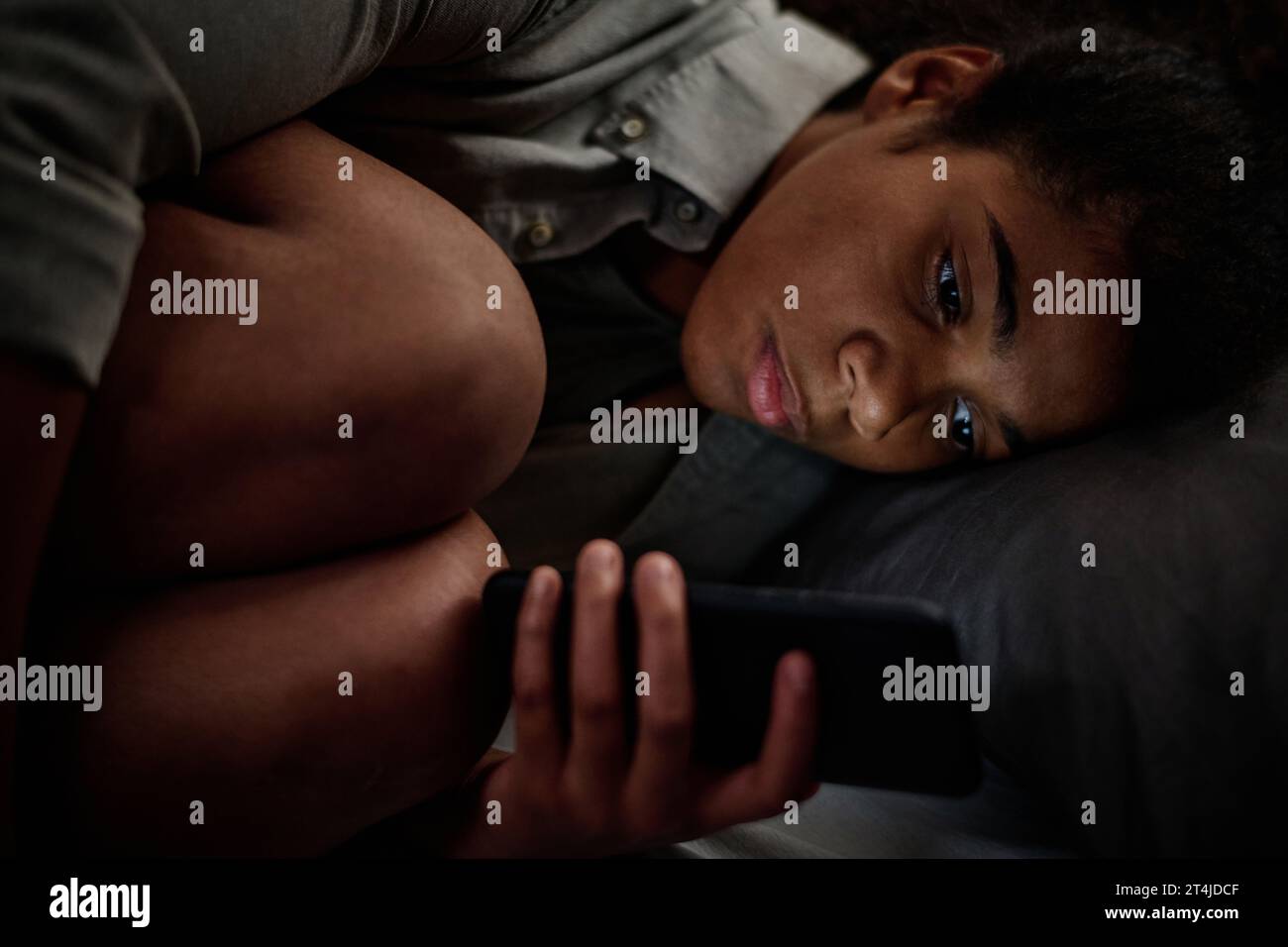 Konzentrieren Sie sich auf das Gesicht eines beunruhigten Teenagers, das während einer Depression spät in der Nacht durch Cybermobbing beleuchtet wird Stockfoto