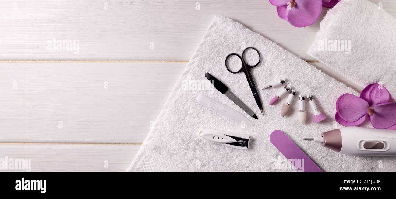 Maniküre-Pediküre-Werkzeugsatz. Nagelbohrmaschine mit Zubehör auf weißem Tisch. Banner mit Kopierbereich. Nagelpflegesalon Stockfoto