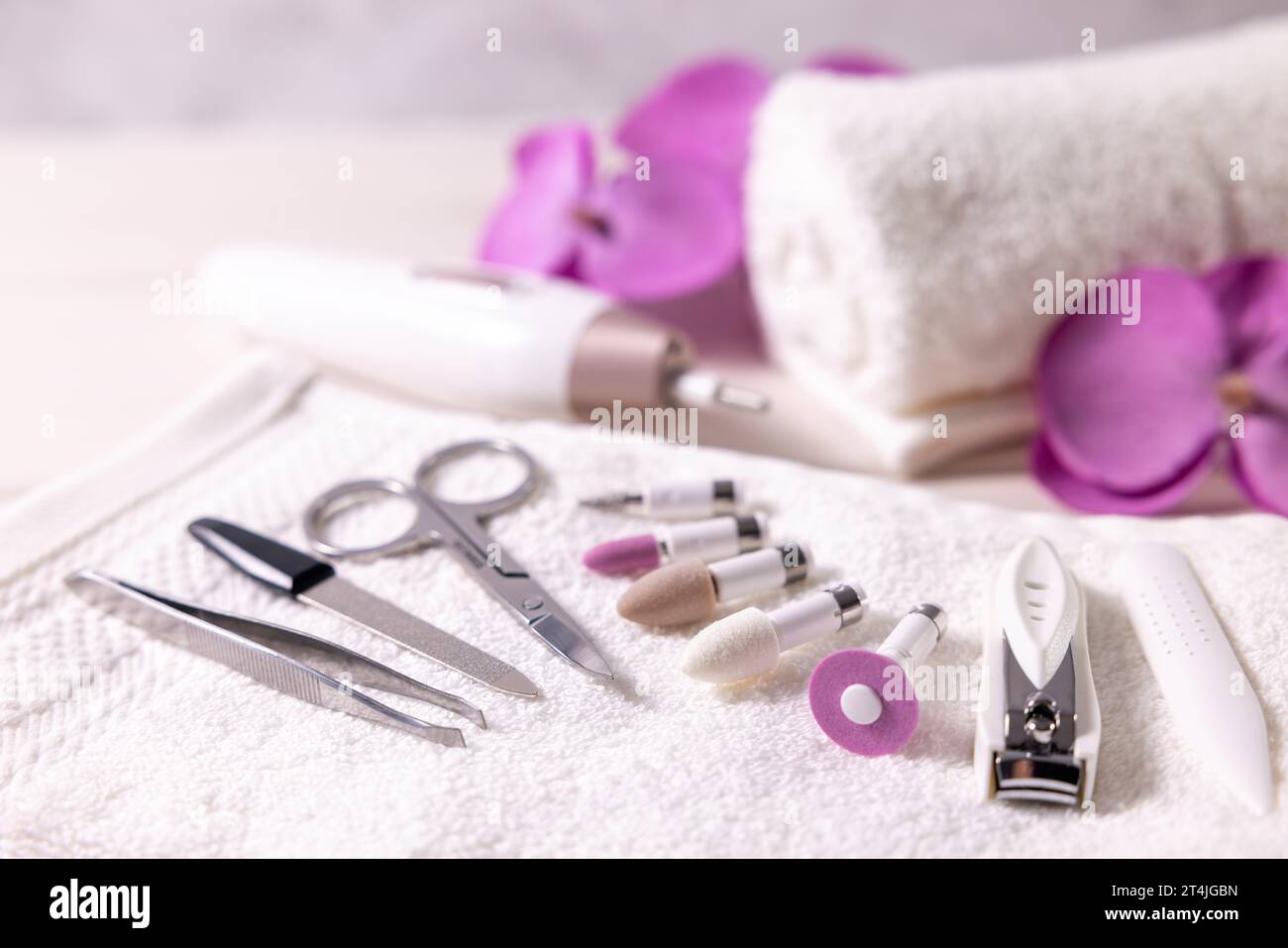 Maniküre-Pediküre-Werkzeugsatz. Nahaufnahme von Nagelbohrern mit anderem Nagelpflegezubehör auf weißem Handtuch. Schönheitsbehandlung Stockfoto