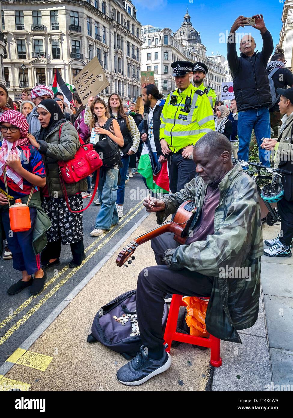 Israel-Gaza-Krieg. Ein Mann spielt Gitarre, während die Demonstranten am 14. Oktober 2023 die Regent Street in London entlang marschieren. Stockfoto