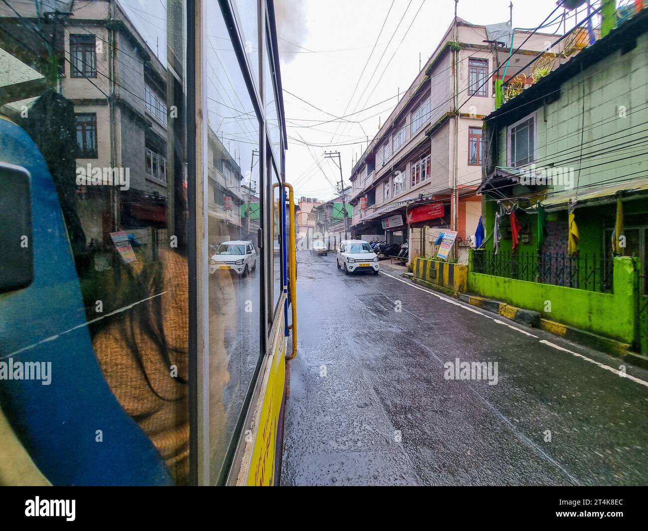 Sehen Sie den Spielzeugzug von außen in darjeeling shimla, der die nasse Straße und Autos zeigt, die auf der Straße fahren und diese berühmte Attraktion zeigen Stockfoto