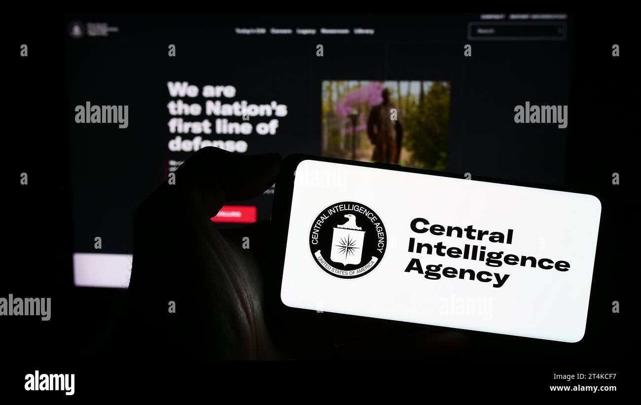 Person, die ein Smartphone mit dem Logo der US-Geheimdienstagentur CIA vor der Website hält. Schwerpunkt auf dem Display des Telefons. Stockfoto