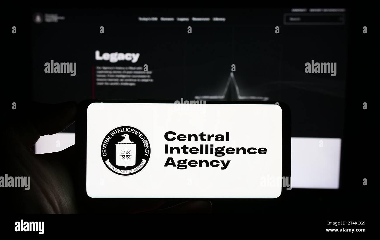 Person, die ein Mobiltelefon hält, mit dem Logo der US-Geheimdienstagentur CIA vor der Webseite. Schwerpunkt auf dem Display des Telefons. Stockfoto