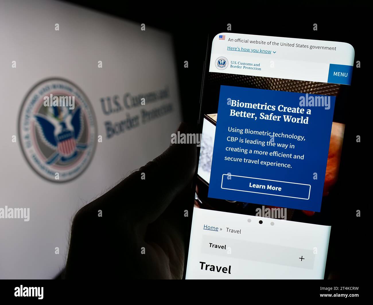 Person, die ein Mobiltelefon mit Webseite der Behörde United States Customs and Border Protection (CBP) mit Siegel hält. Konzentrieren Sie sich auf die Mitte des Telefondisplays. Stockfoto