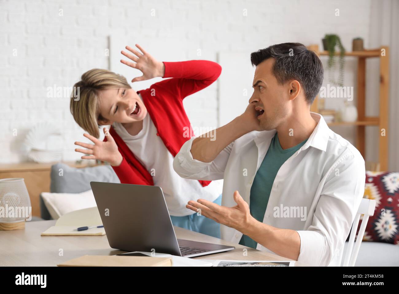 Ein junger Mann, der von seinem lauten Sohn zu Hause gestresst ist Stockfoto