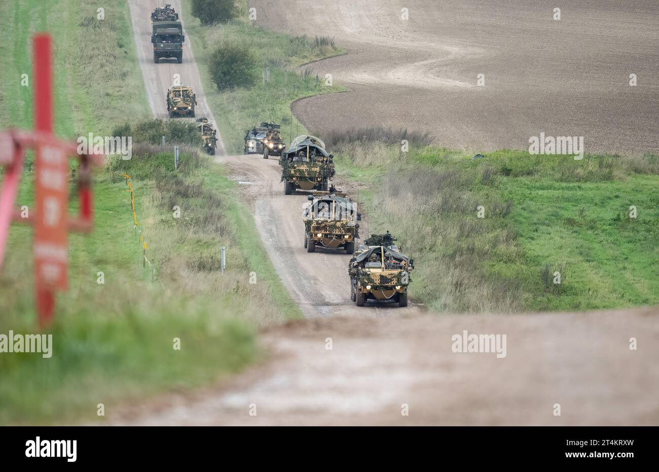 Ein Konvoi von getarnten britischen Militärfahrzeugen, die auf einem Feldweg unterwegs sind Stockfoto