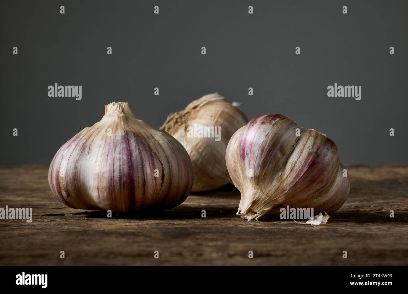 Frischer roher Knoblauch auf Holzbrett auf dunklem Hintergrund Stockfoto