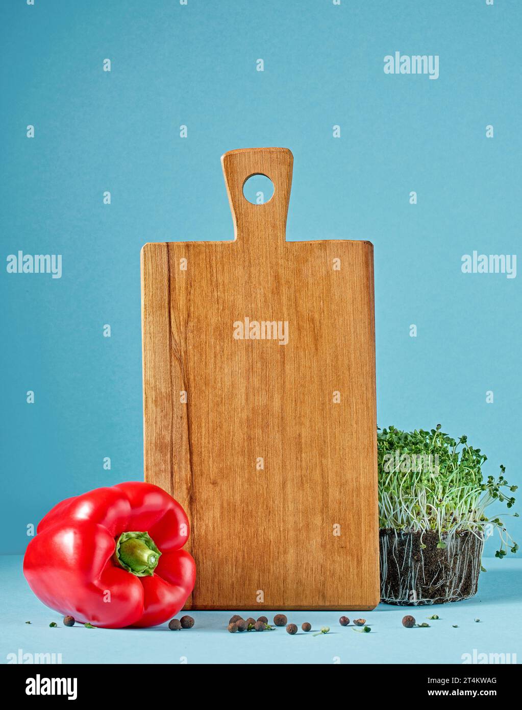Stillleben mit hölzernem Schneidebrett und Gemüse auf blauem Hintergrund Stockfoto