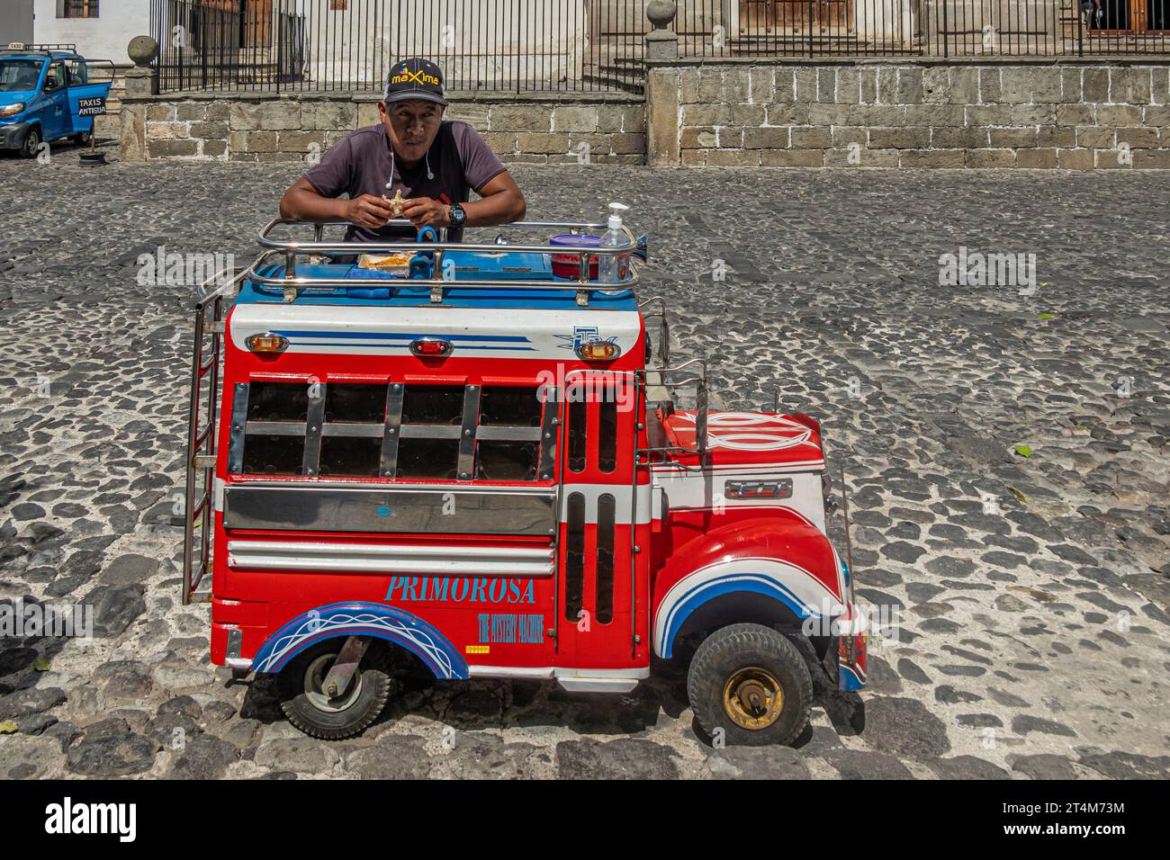 Guatemala, La Antigua - 20. Juli 2023: Ein Mann, der sein Sandwich isst, mit seinem Primorosa, der Mysterienmaschine, roter Kinderwagen auf dem zentralen Platz, Plaz Stockfoto