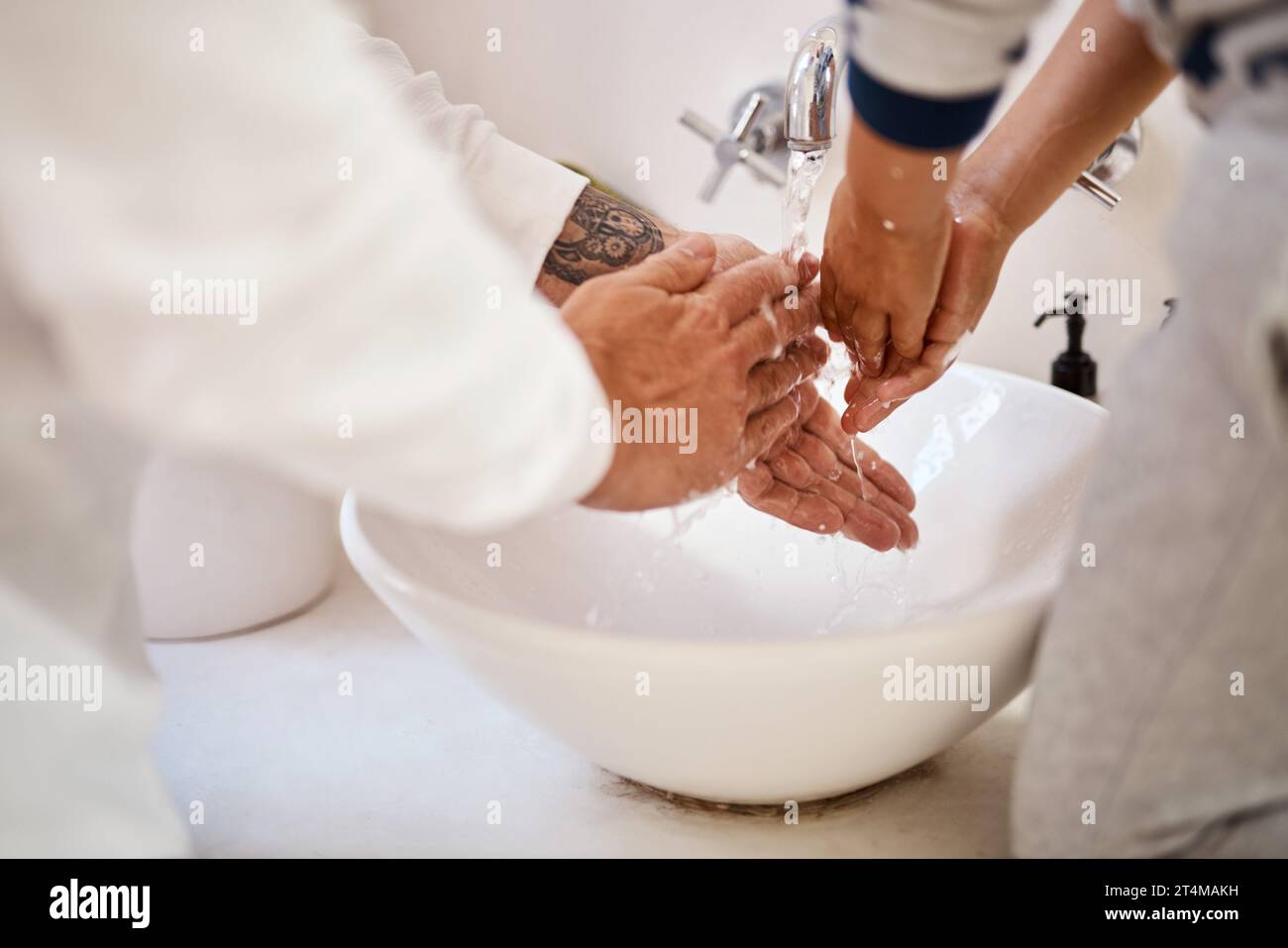 Aufschäumen und abspülen. Ein Mann und sein Sohn waschen sich die Hände im Bad. Stockfoto