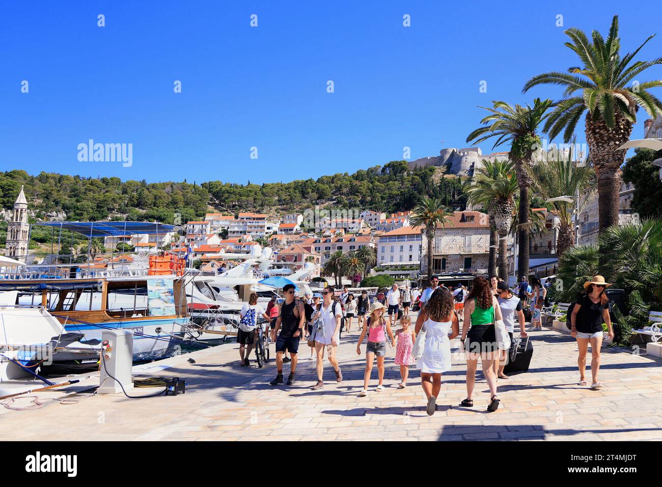 Touristen genießen Hvar, einschließlich Hafen und Festung auf dem Hügel, Kroatien Stockfoto