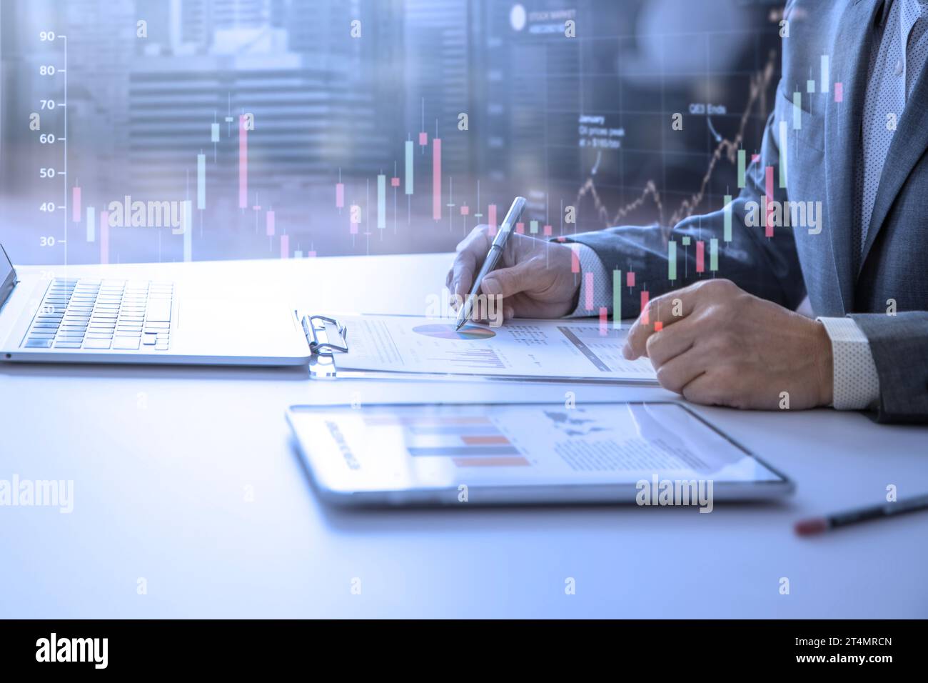 Geschäftsmann, der im Büro mit einem modernen Tablet und einem Laptop die Finanzberichte überprüft, um eine Kapitalrendite zu erzielen. Stockfoto