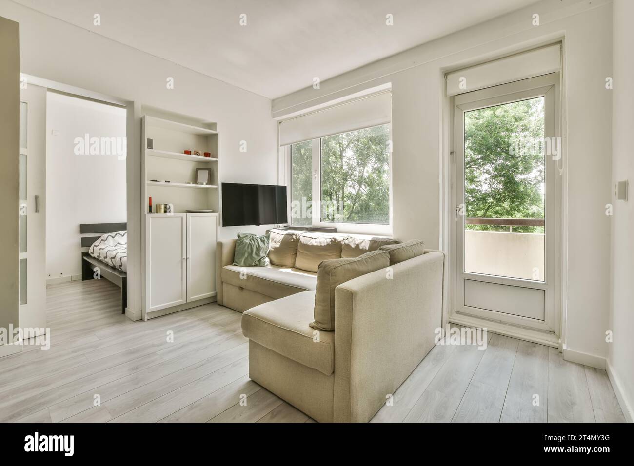 Ein Wohnzimmer mit weißen Wänden und Holzfußboden. Das Zimmer ist in neutralen Tönen, einschließlich in hellen Grautönen, eingerichtet Stockfoto