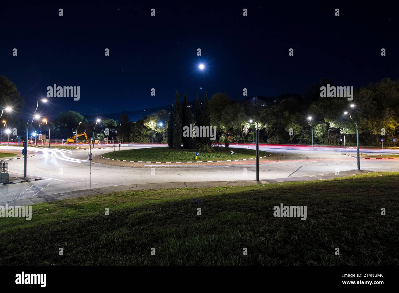 Ein Kreisverkehr in einer schnellen Straße in einer italienischen Stadt bei Nacht, mit einigen Autolichtern in beide Richtungen. Stockfoto