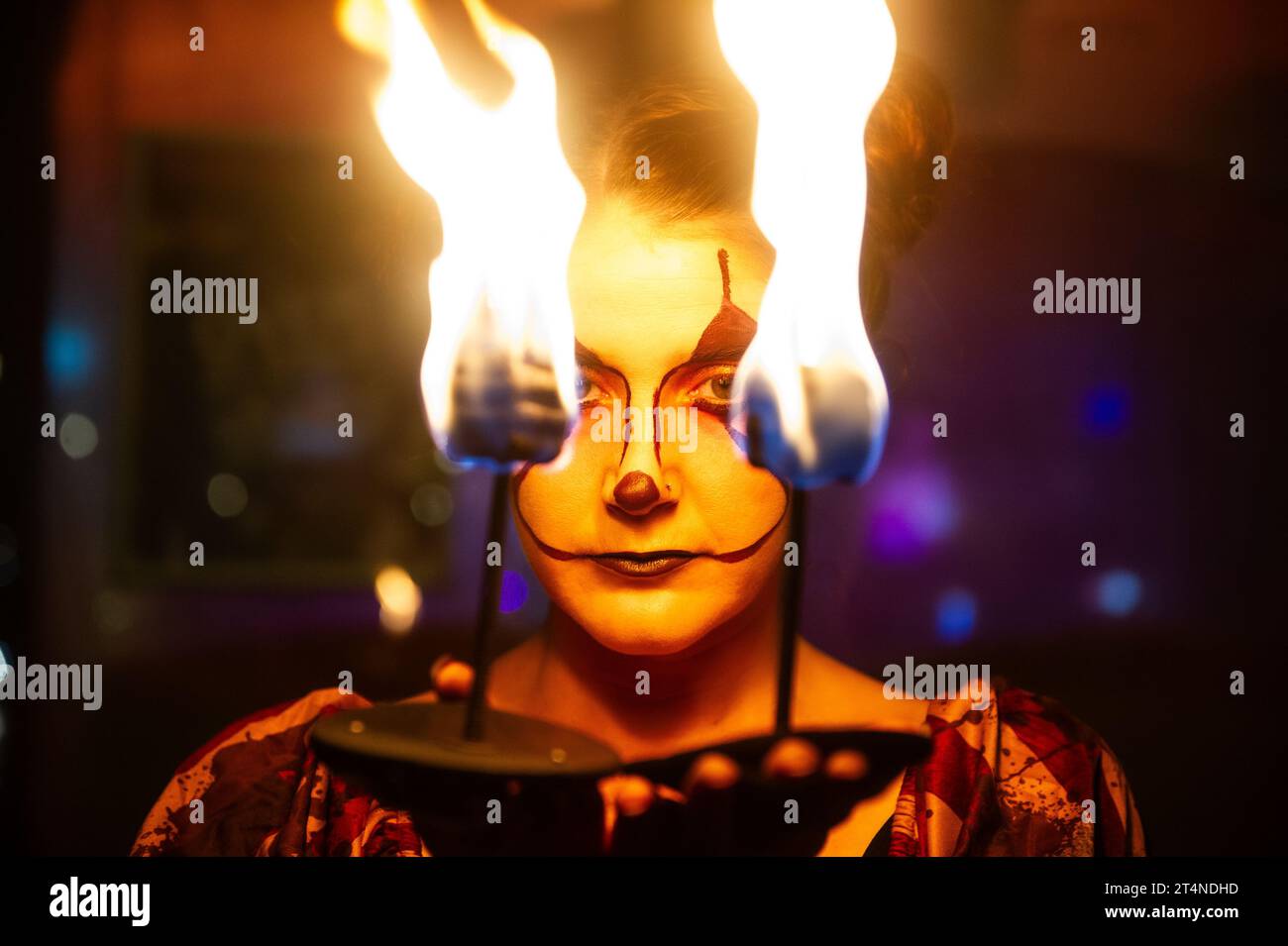 Die Frau führt am halloween-Wochenende Feuer atmet und isst, um die Leute in den Nachtclub zu locken, verkleidet als Gothic Narr. Stockfoto