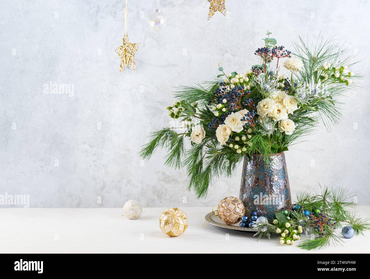 Weihnachtsdekoration, Kerzen und Blumenstrauß. Winterarrangements mit Rosen, Tannenzweigen, Winterbeeren. Weihnachtsblumen-Stillleben. Stockfoto