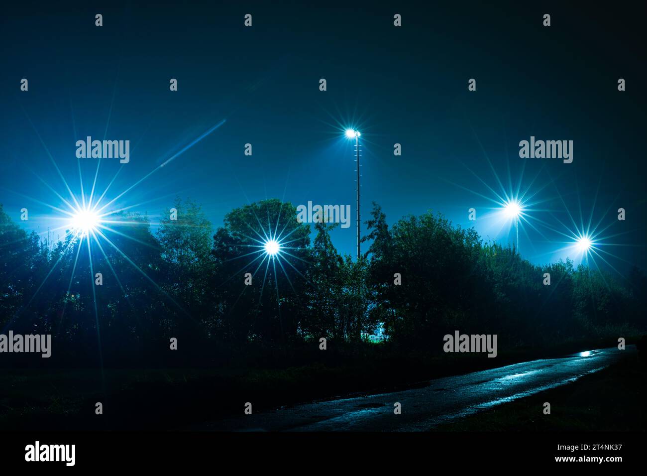 Lichtmasten mit hellen Lichtern in der Nähe eines Sportplatzes Stockfoto