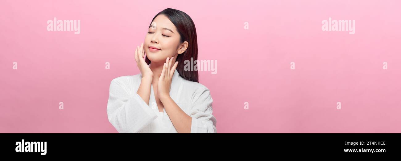 Schöne junge asiatische Frau mit sauberer, frischer Haut auf rosa Hintergrund, Panorama Stockfoto