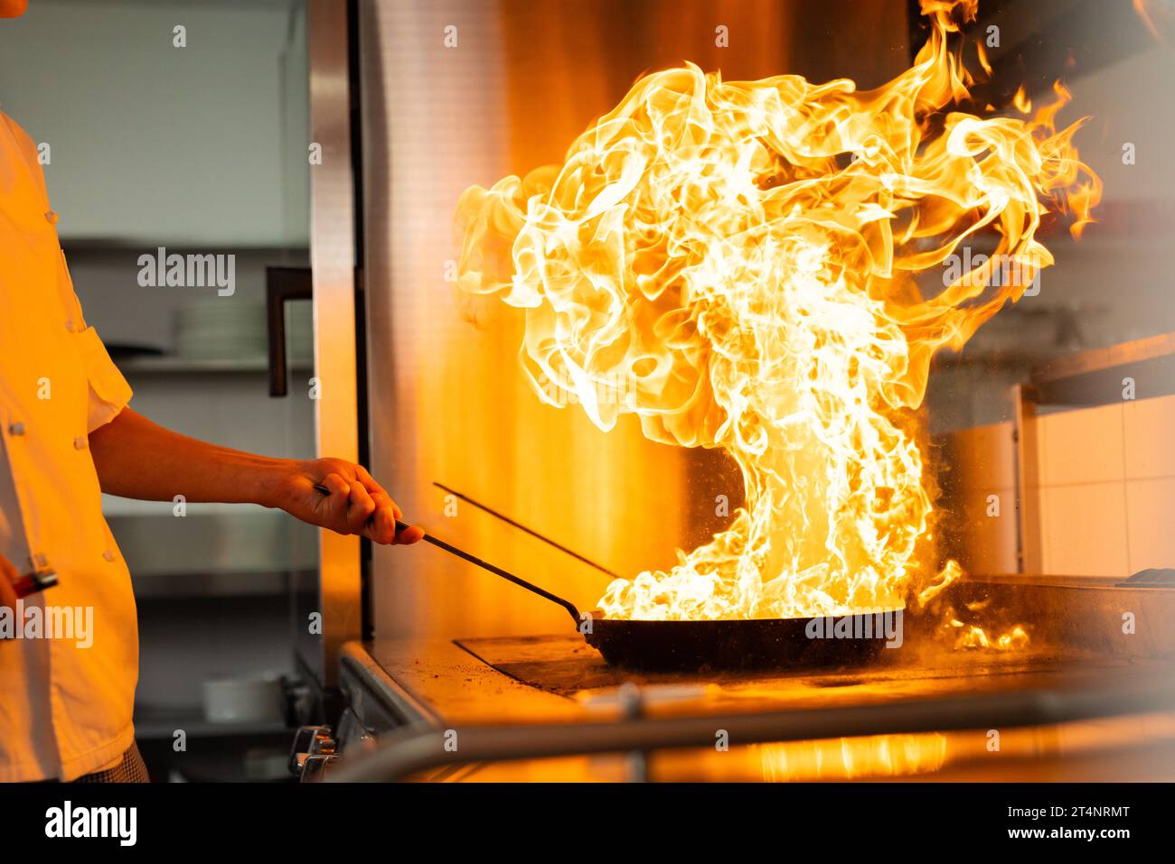 Kaukasischer männlicher Koch kocht mit Pfanne mit Kamin in der Restaurantküche, Kopierraum Stockfoto