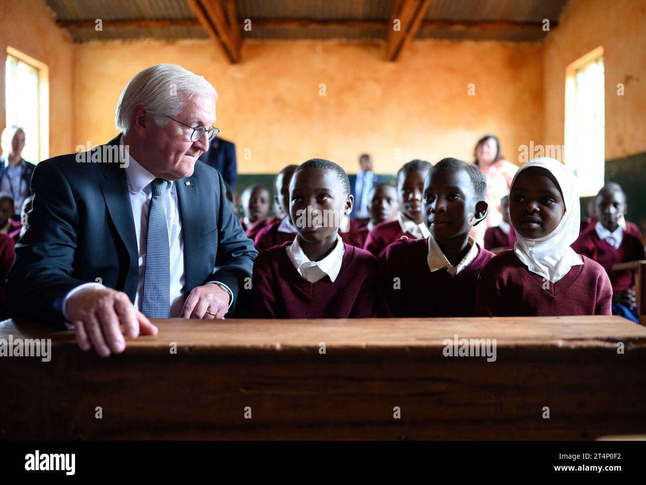 Songea, Tansania. November 2023. Bundespräsident Frank-Walter Steinmeier sitzt neben Schulmädchen in einer Klasse an der Maji-Maji Primary School in Songea. Er beendete seine Tansania-Reise am Mittwoch mit einem Beitrag zur Auseinandersetzung mit der deutschen Kolonialgeschichte und traf auch Familien in Songea, deren Vorfahren in einem brutalen Krieg in der Kolonie Deutsch-Ostafrika starben. Quelle: Bernd von Jutrczenka/dpa/Alamy Live News Stockfoto