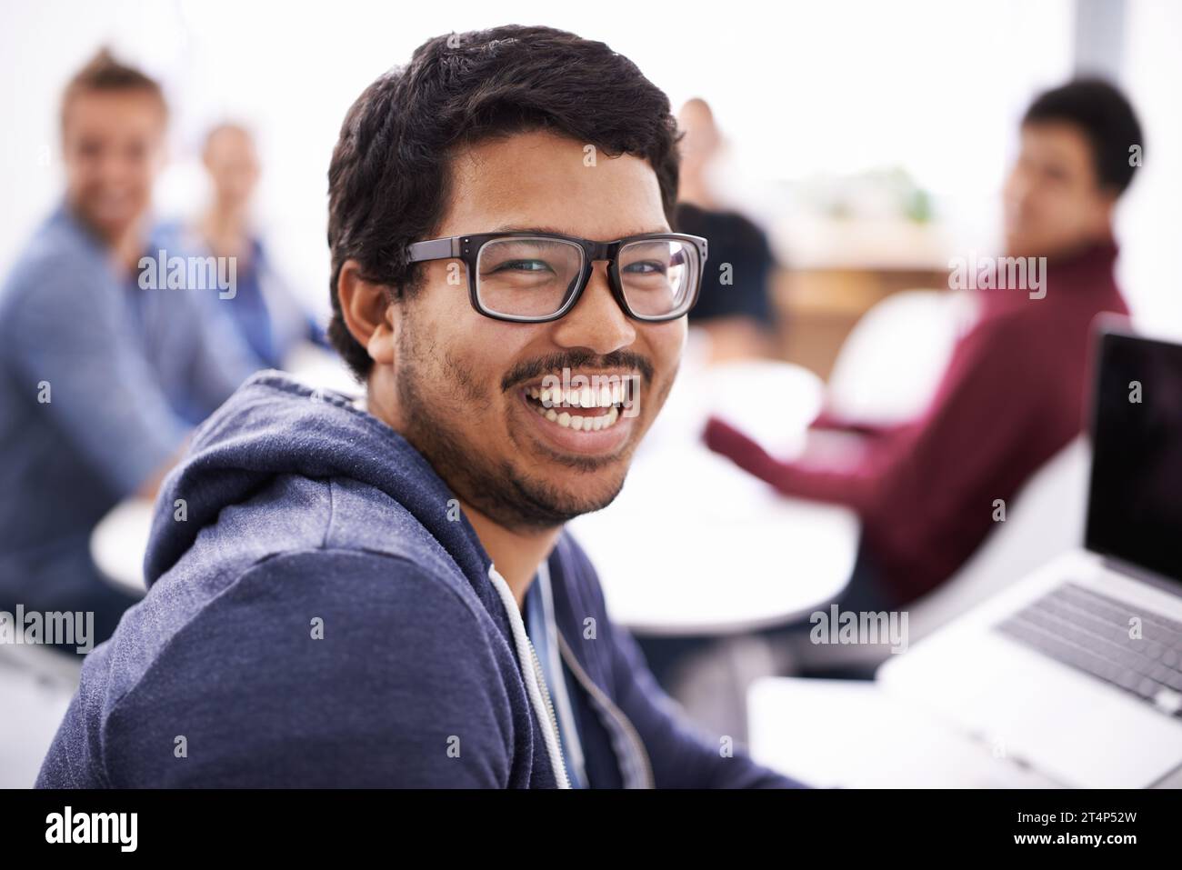 Arbeit kann Spaß machen. Ein junger Mann, der in einem Büro an seinem Laptop arbeitet. Stockfoto