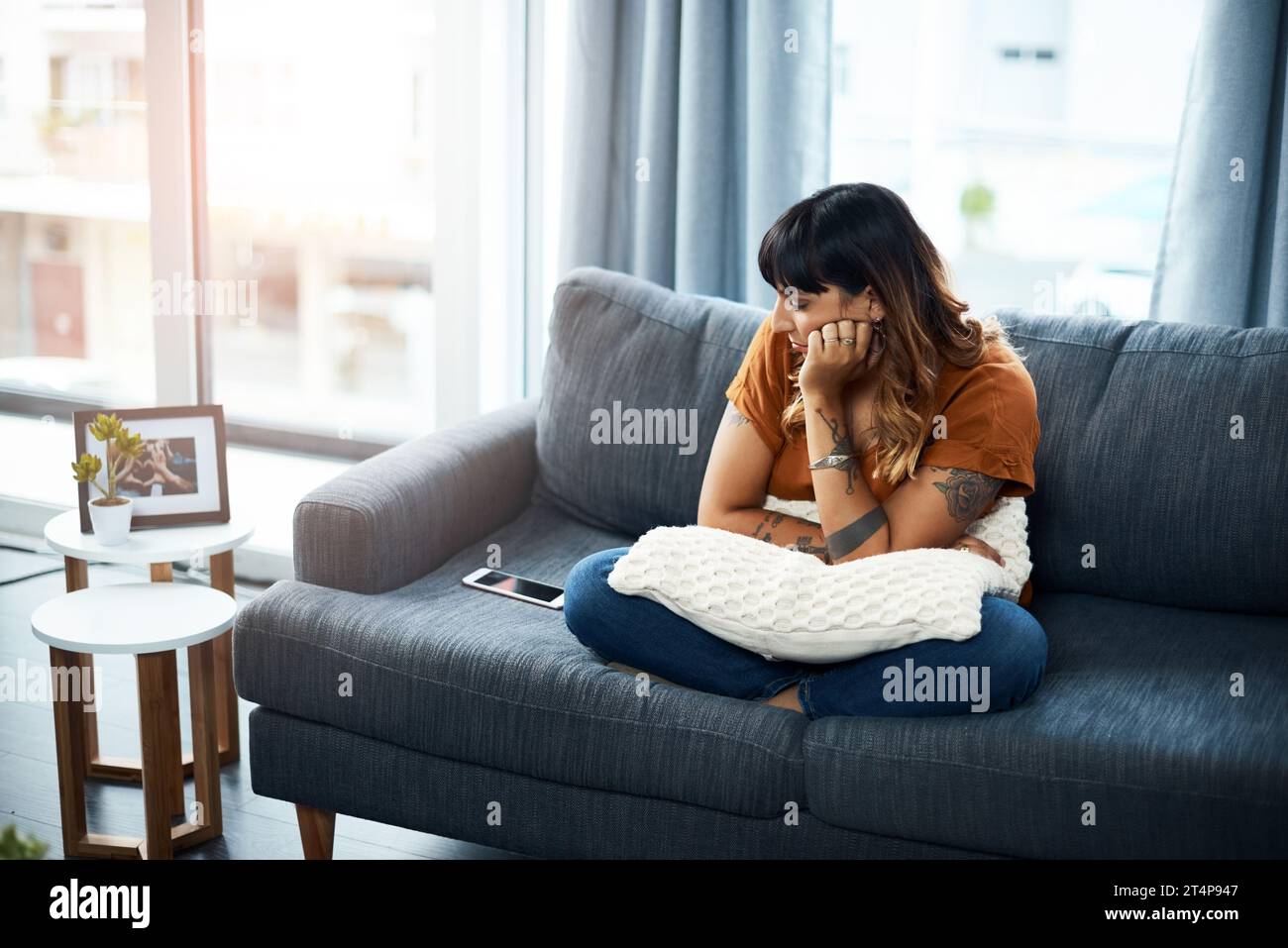 Ich warte immer noch auf seinen Anruf. Eine Frau, die verärgert aussieht, während sie ihr Handy anstarrt. Stockfoto