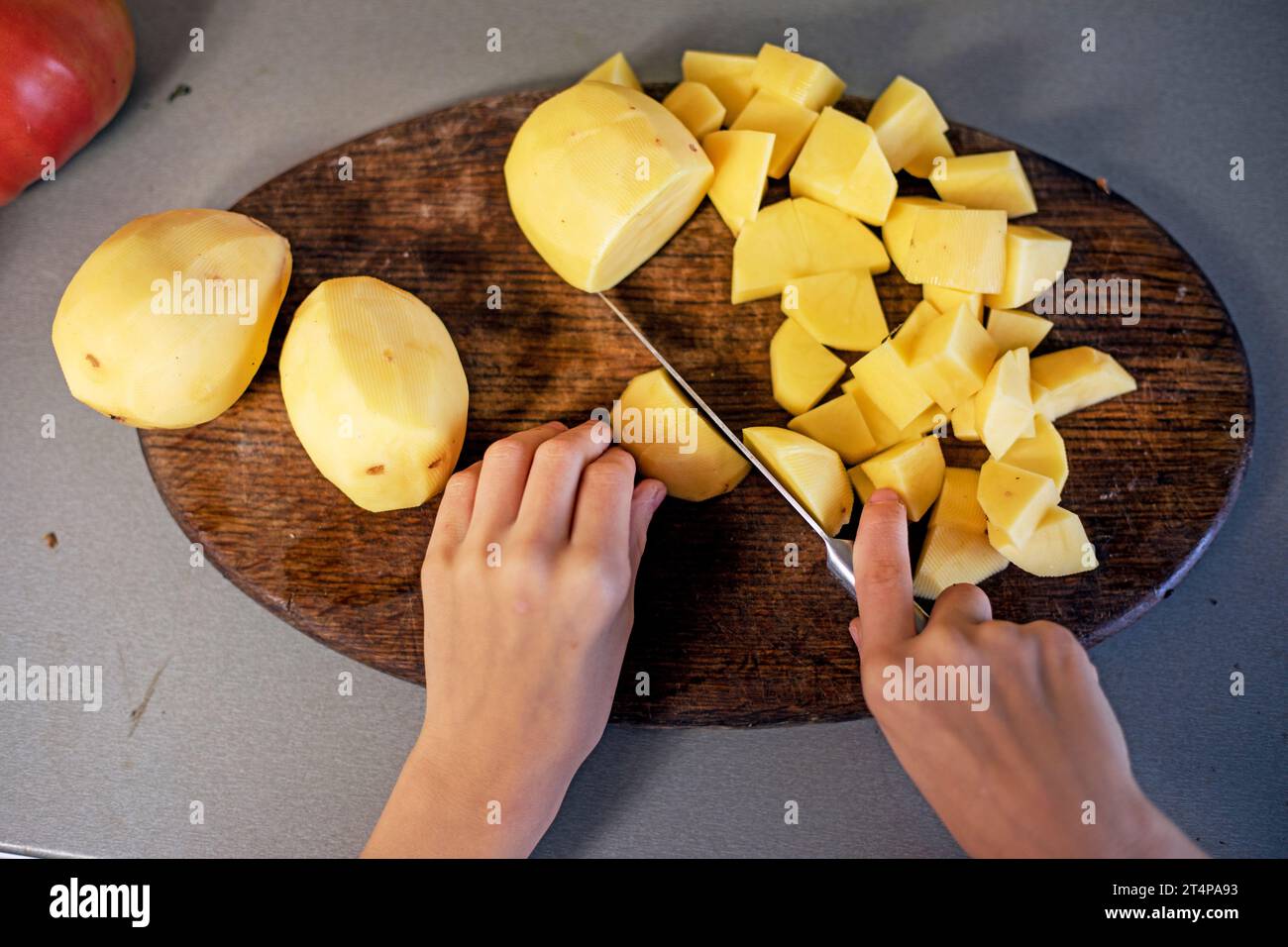 Schneiden Sie Kartoffeln mit einem Messer auf einem Schneidebrett in kleine Stücke. Abwicklung Stockfoto