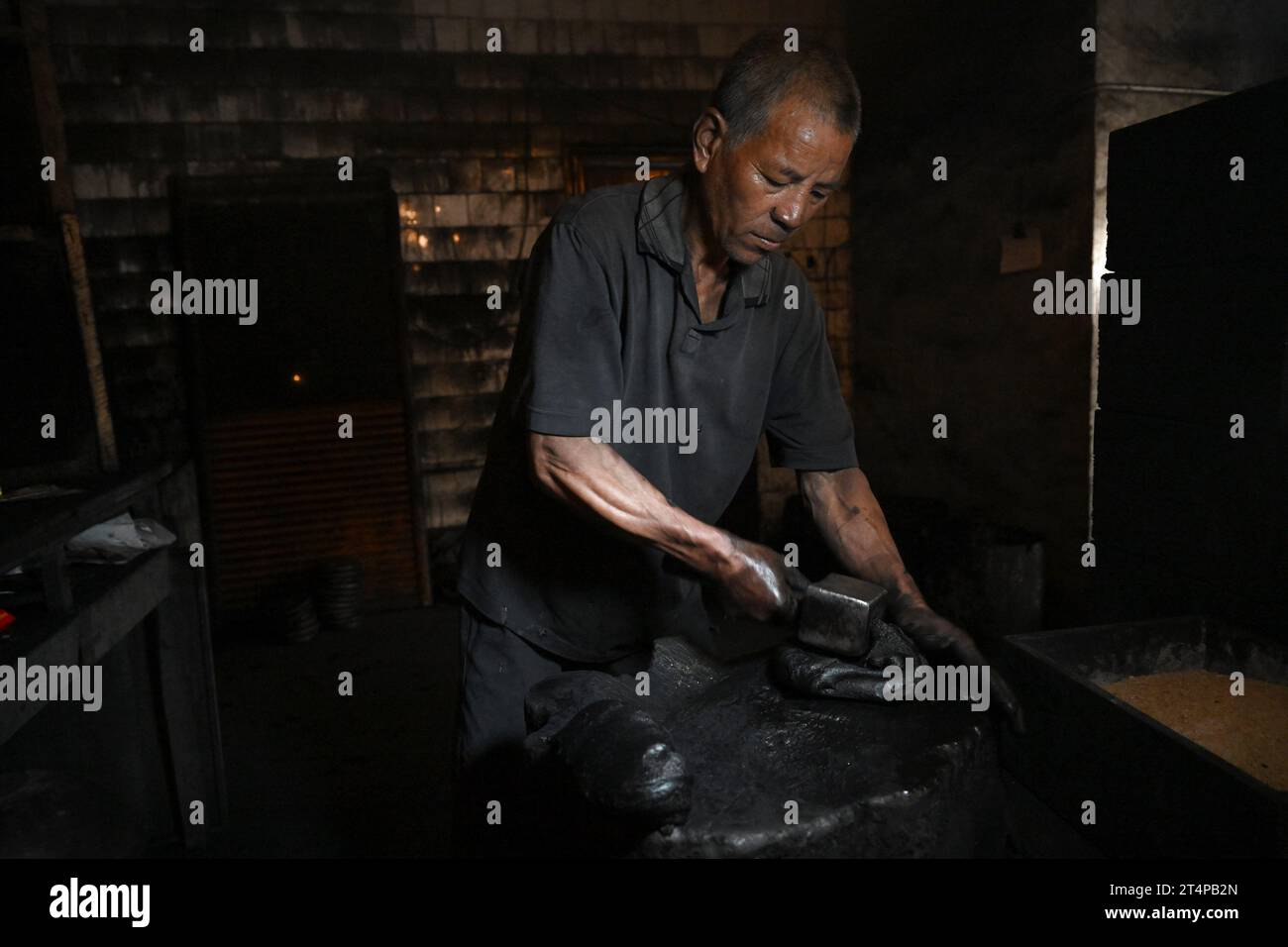 (231031) -- SHEXIAN COUNTY, 31. Oktober 2023 (Xinhua) -- Ein Arbeiter hämmert einen Tintenkuchen in einer Werkstatt der alten Hu Kaiwen Tintenfabrik im Shexian County, Stadt Huangshan in der ostchinesischen Provinz Anhui, 25. Oktober 2023. Shexian County, das sich in der Stadt Huangshan in der ostchinesischen Provinz Anhui befindet, ist als „Hauptstadt der Tinte“ bekannt, die auf die südliche Tang-Dynastie (937–975) zurückgeht. Nachdem sie 1121 in Huizhou umbenannt wurde, steht der Begriff „Huizhou Ink“ oder „Hui Mo“ auf Chinesisch für qualitativ hochwertiges Tintenprodukt in China. Huizhou Ink, eine Art Farbe, die normalerweise in der traditionellen chinesischen Kalligraphie und Pinselschmerz angewendet wird Stockfoto