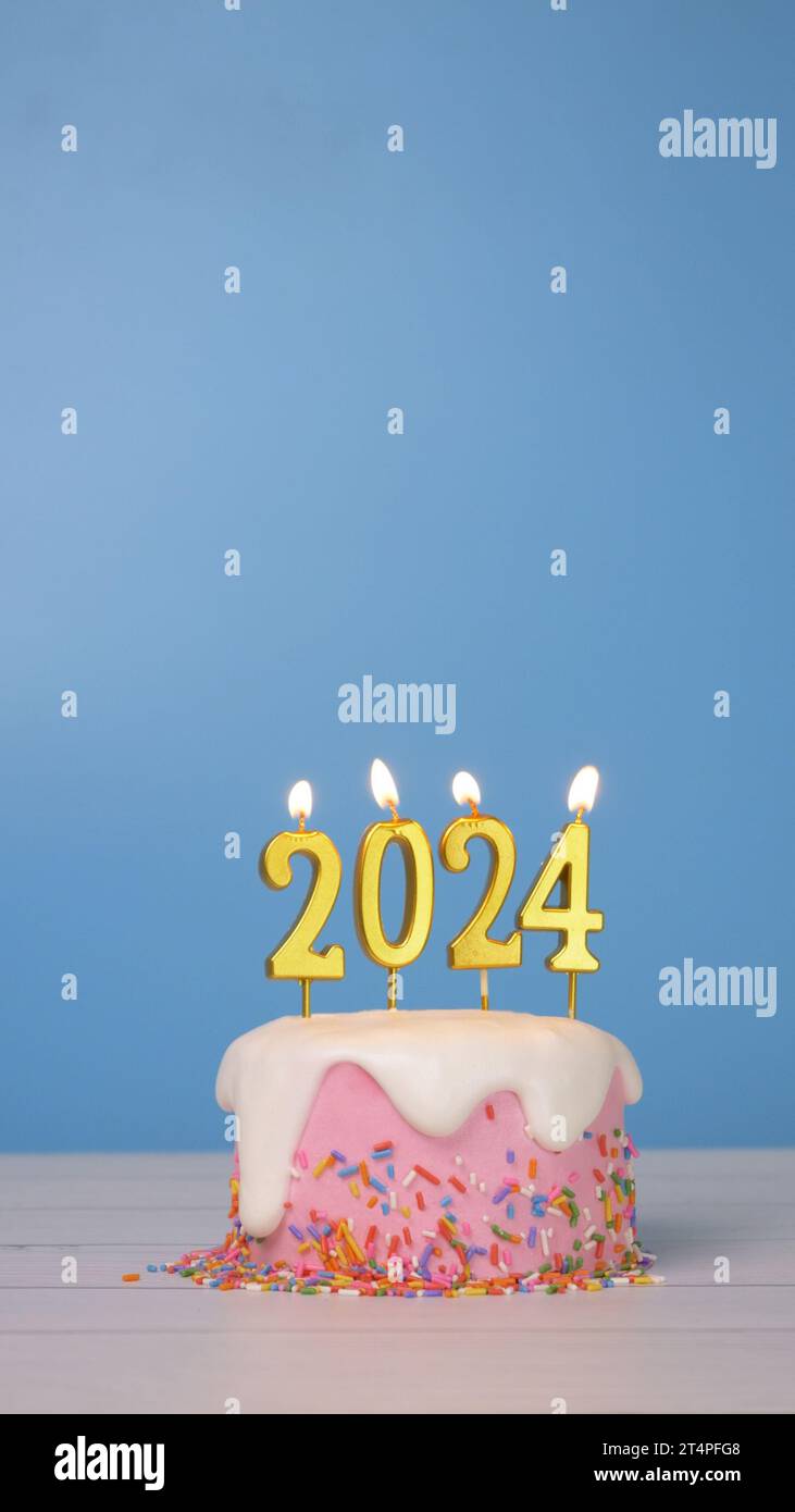 Happy New Year 2024, rosa Geburtstagskuchen dekorieren mit bunten Zuckerstreuseln und Schlagsahne mit goldener Kerze 2024 für Neujahrsfeier Stockfoto