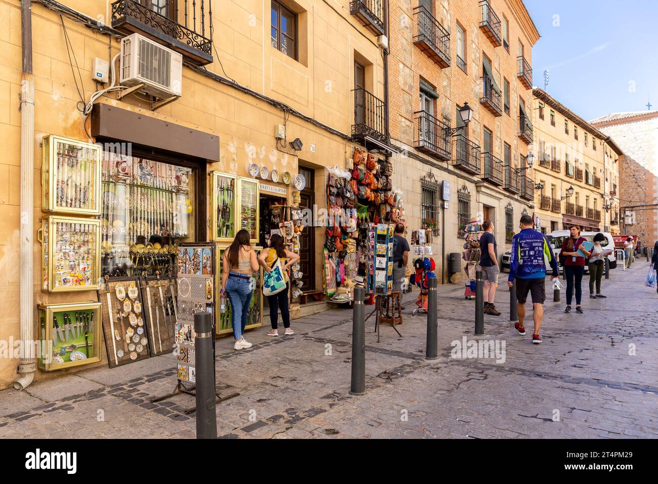 Toledo, Spanien, 08.10.21. Souvenirladen in einer engen mittelalterlichen Straße mit Töpferwaren, mittelalterlichen Schwertern, Korktaschen und Hüten, Postkarten und Touristen. Stockfoto