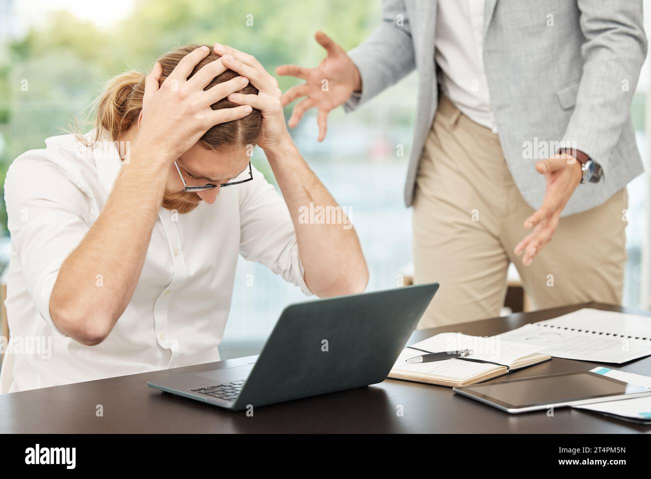 Ich ertrinke unter all diesen Forderungen. Ein junger Geschäftsmann, der bei einem Streit mit einem Kollegen in einem Büro gestresst aussieht. Stockfoto