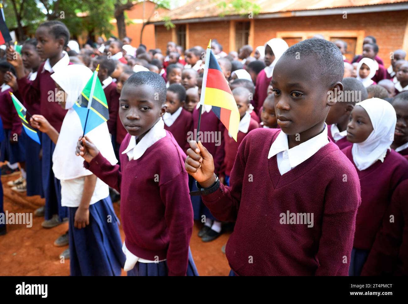 Songea, Tansania. November 2023. Schüler der Maji-Maji-Grundschule in Songea stehen während des Besuchs von Präsident Steinmeier auf dem Schulhof mit deutschen und tansanischen Fahnen. Steinmeier beendete seine Tansania-Reise am Mittwoch mit seinem Besuch in Songea. Quelle: Bernd von Jutrczenka/dpa/Alamy Live News Stockfoto