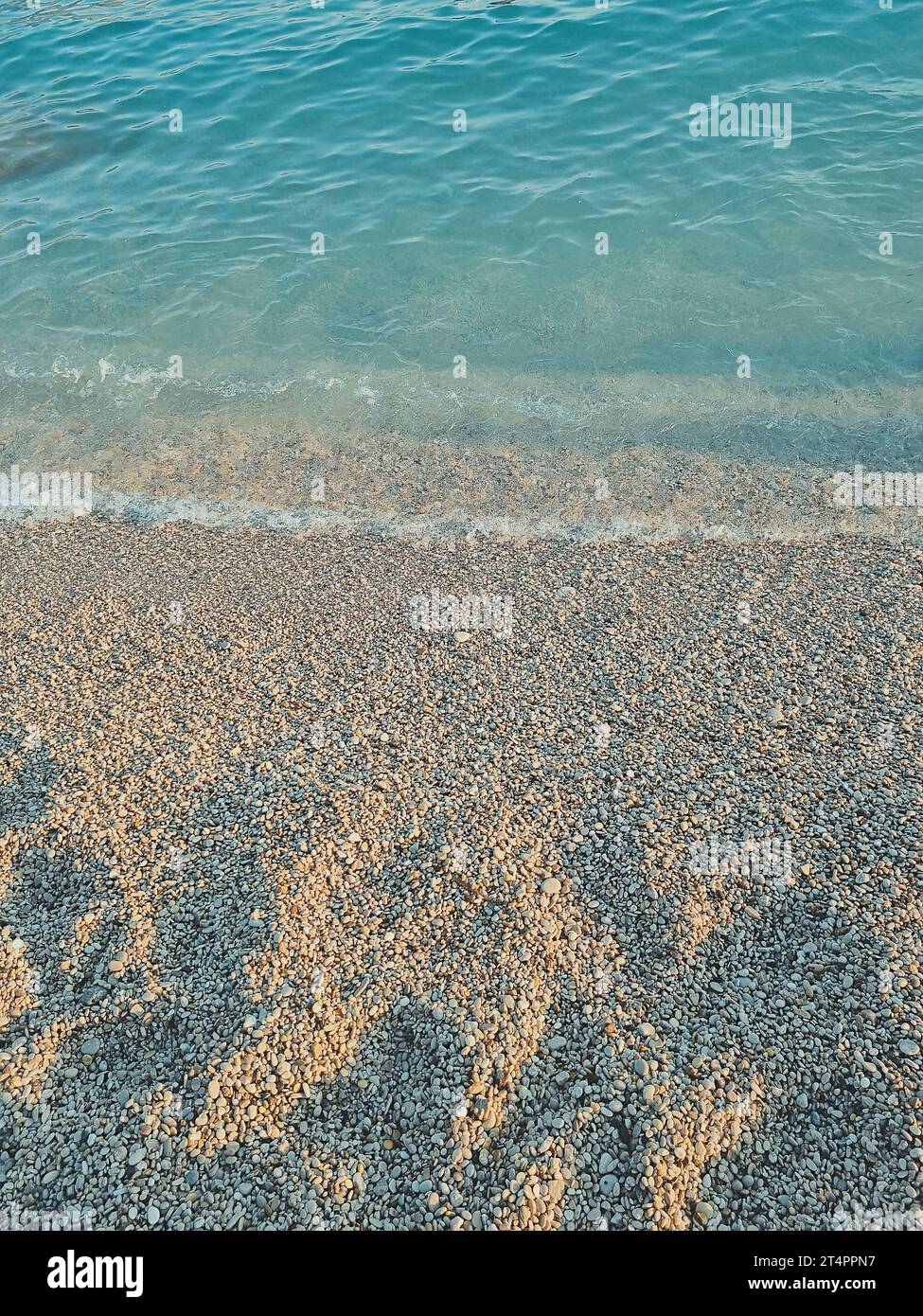 Vertikales Foto des klaren blauen Meeres und des Kieselstrands. Sommerurlaubskonzept am Strand. Weichzeichner. Kopierbereich Stockfoto