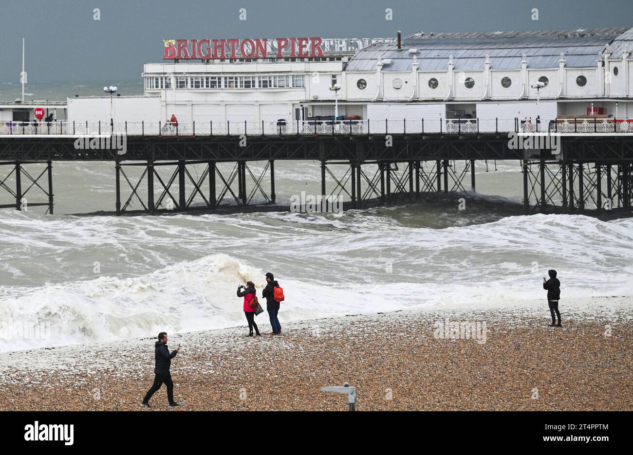 Brighton UK 1. November 2023 - Besucher beobachten, wie die Wellen bei starkem Wind auf Brighton am Pier stürmen, während Storm Ciaran sich Großbritannien nähert und für einige Teile Großbritanniens gelbe und gelbe Wetterwarnungen ausgegeben werden: Credit Simon Dack / Alamy Live News Stockfoto