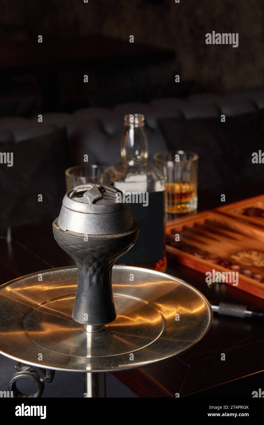 Hookah, Flasche und Glas Whiskey, Backgammon Board auf Tisch in dunklen Bar. Konzept der zusammen Ausruhen nach harten Tag. Stockfoto