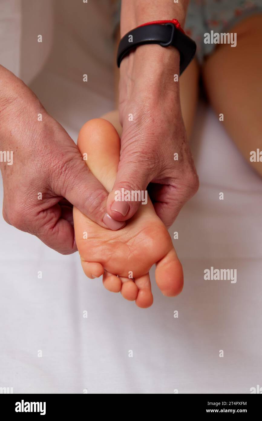 Hände eines kompetenten Massagetherapeuten, die den Fuß an das Kind massieren, um die Entwicklung von Plattfüßen zu verhindern Stockfoto