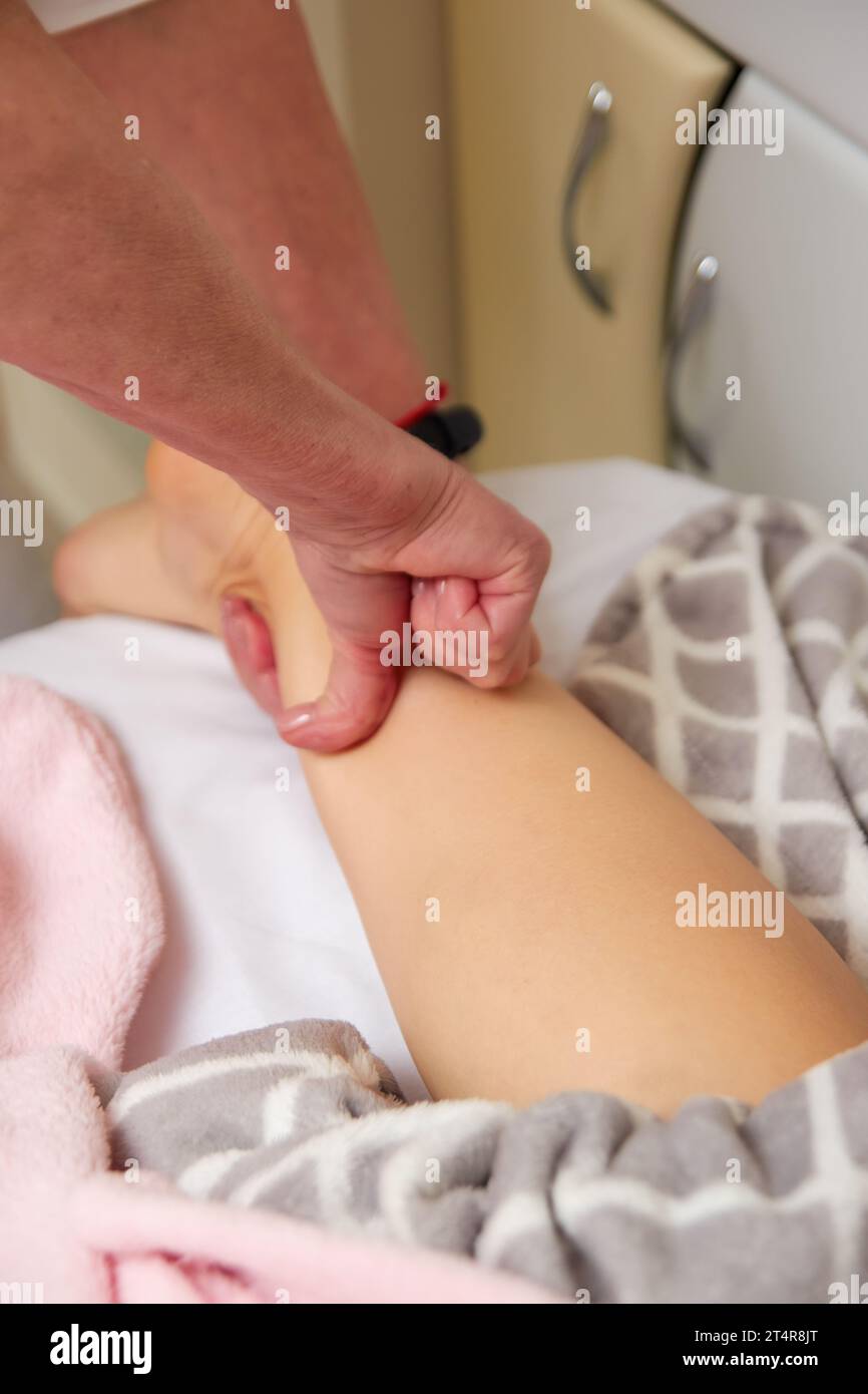 Großaufnahme der Hände eines professionellen Massagetherapeuten, der Lymphdrainage-Beine-Massage für weibliche Klientin im Spa-Center durchführt Stockfoto