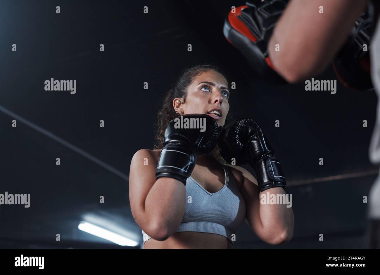 Eine großartige Möglichkeit, fit zu werden und sich selbst zu schützen. Eine junge Frau, die mit ihrem Trainer in einer Boxhalle trainiert. Stockfoto