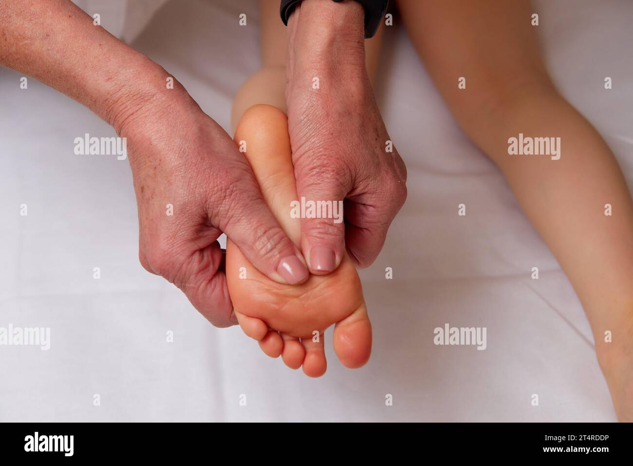 Großaufnahme der Hände eines Facharztes, der eine pädiatrische Fußmassage zur Verbesserung der Durchblutung im Kinderkörper durchführt Stockfoto