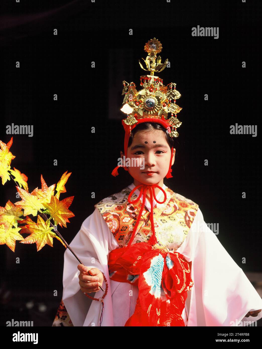 Japan. Tokio. Herbstfest. Einheimisches Mädchen in traditioneller Kleidung, das Ahornzweig hält. Stockfoto