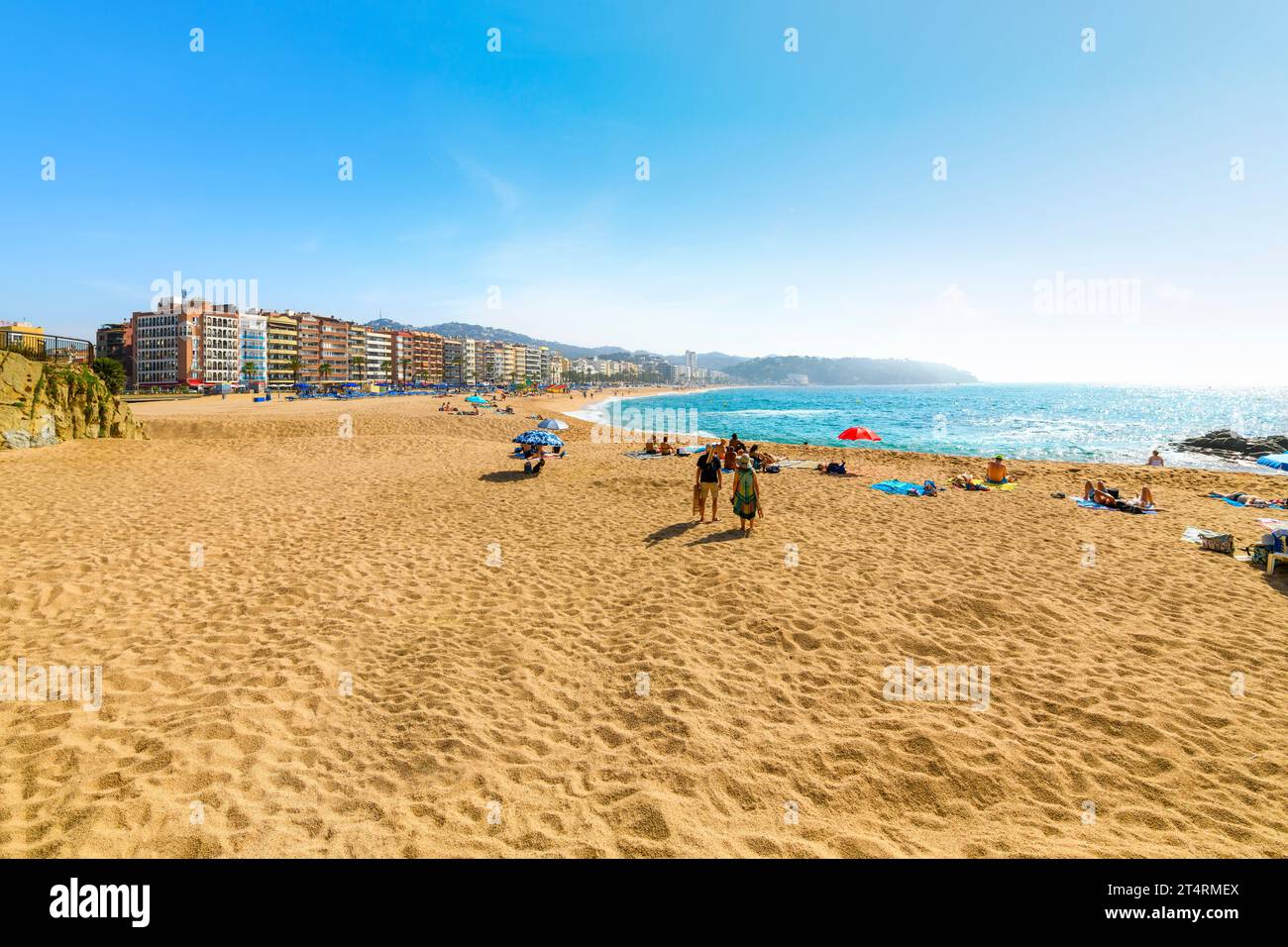 Spanier und Touristen genießen einen Sommertag am breiten Sandstrand Playa Grande im spanischen Ferienort Lloret de Mar an der Costa Brava. Stockfoto